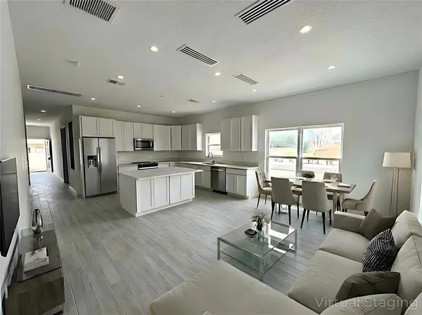 a living room kitchen with furniture and a wooden floor