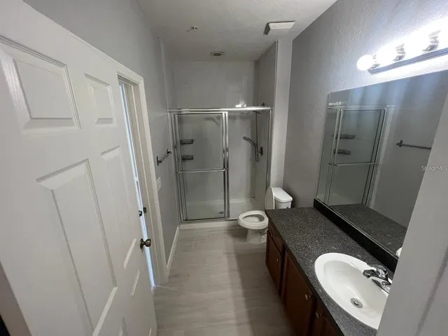 a bathroom with a granite countertop sink toilet and shower