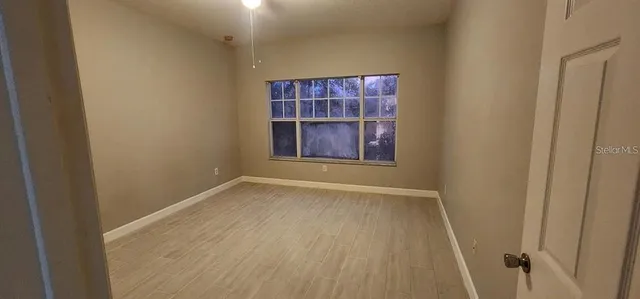 a view of an empty room with wooden floor and staircase