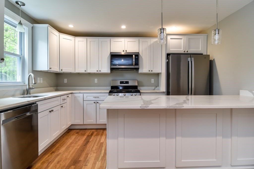 8 Everett Street Sherborn, MA 01770 - Photo 10 of 25 a kitchen with stainless steel appliances granite countertop a refrigerator a sink dishwasher a stove and white cabinets with wooden floor