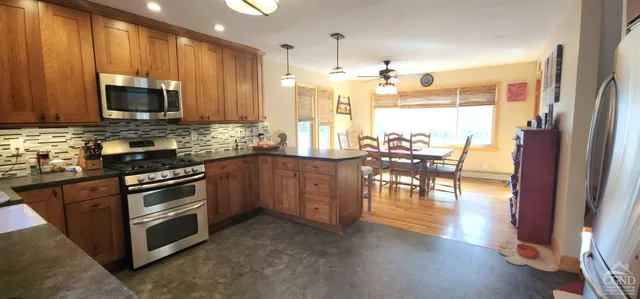 a kitchen with stainless steel appliances granite countertop a stove top oven a sink dishwasher a dining table and chairs with wooden floor