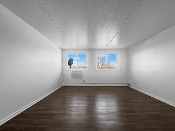 an empty room with wooden floor and windows