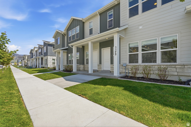 1173 West 1870 South Logan, UT 84321 - Photo 26 of 33 Contemporary townhome exterior featuring light gray siding with dark gray vertical accents, stone veneer foundation, white trim, and a covered entryway