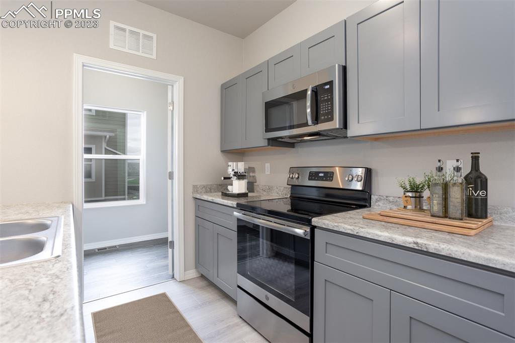 4447 Samaritan Loop Colorado Springs, CO 80916 - Photo 11 of 17 a kitchen with stainless steel appliances granite countertop white cabinets a microwave oven and a sink