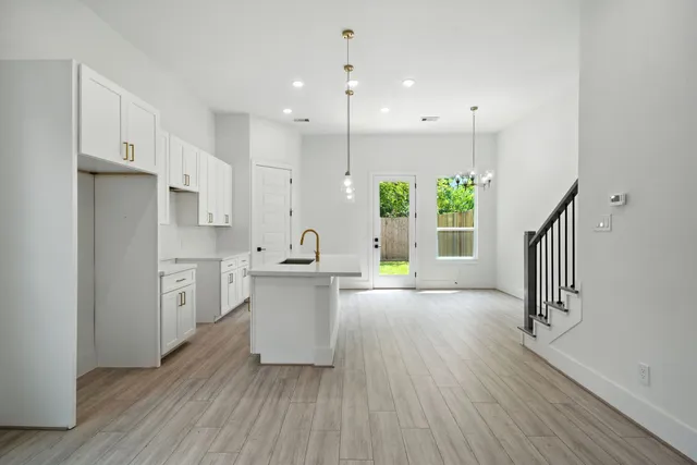 a kitchen with white cabinets and wooden floors