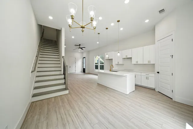 a large white kitchen with a large kitchen island white cabinetry and stainless steel appliances