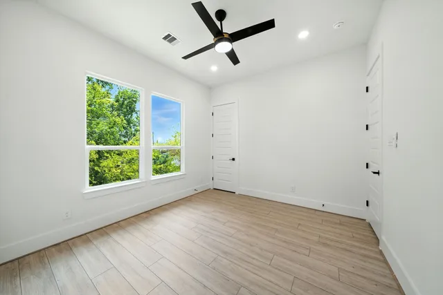 an empty room with wooden floor and windows
