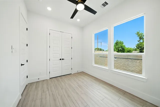 a view of an empty room with a window and wooden floor