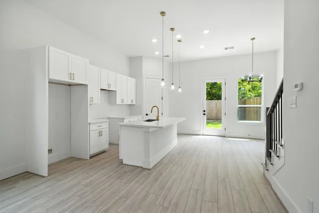 a large kitchen with white cabinets a sink a window and stainless steel appliances