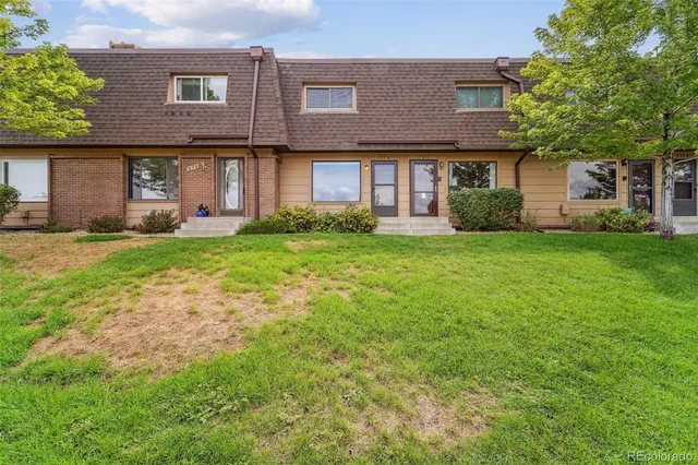 a view of a brick house with a big yard and large trees