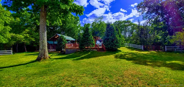a view of a park with large trees and a barn in it