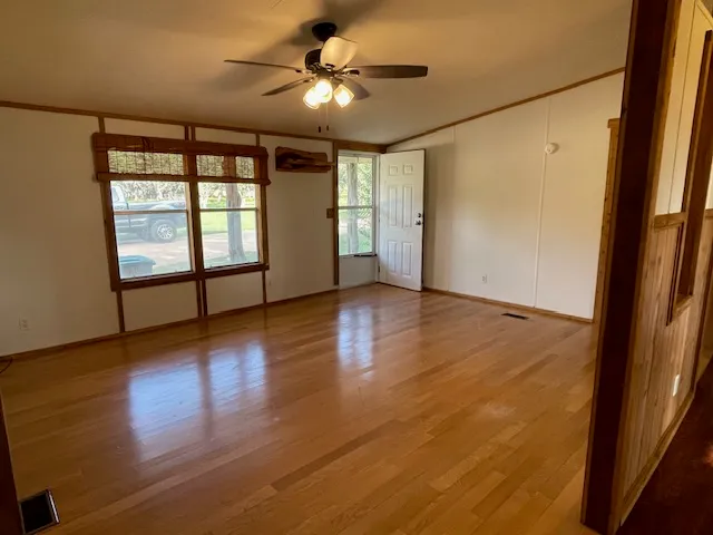 an empty room with wooden floor and windows