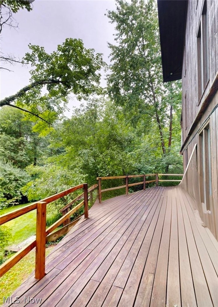 2868 Shade Road Akron, OH 44333 - Photo 42 of 49 Expansive wood-finish deck with natural wood railing, surrounded by mature trees and lush greenery
