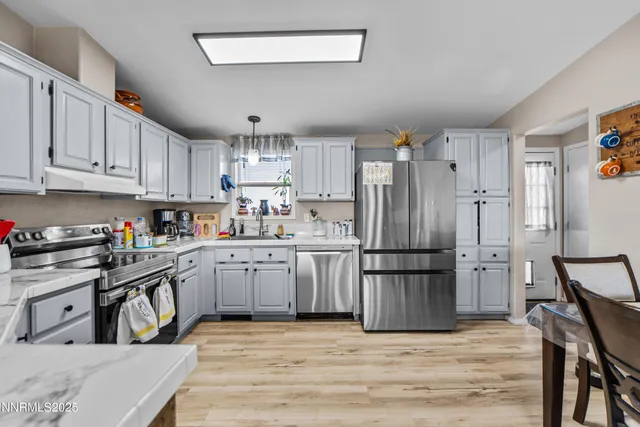 a kitchen with granite countertop a refrigerator stove a sink and dishwasher with wooden floor