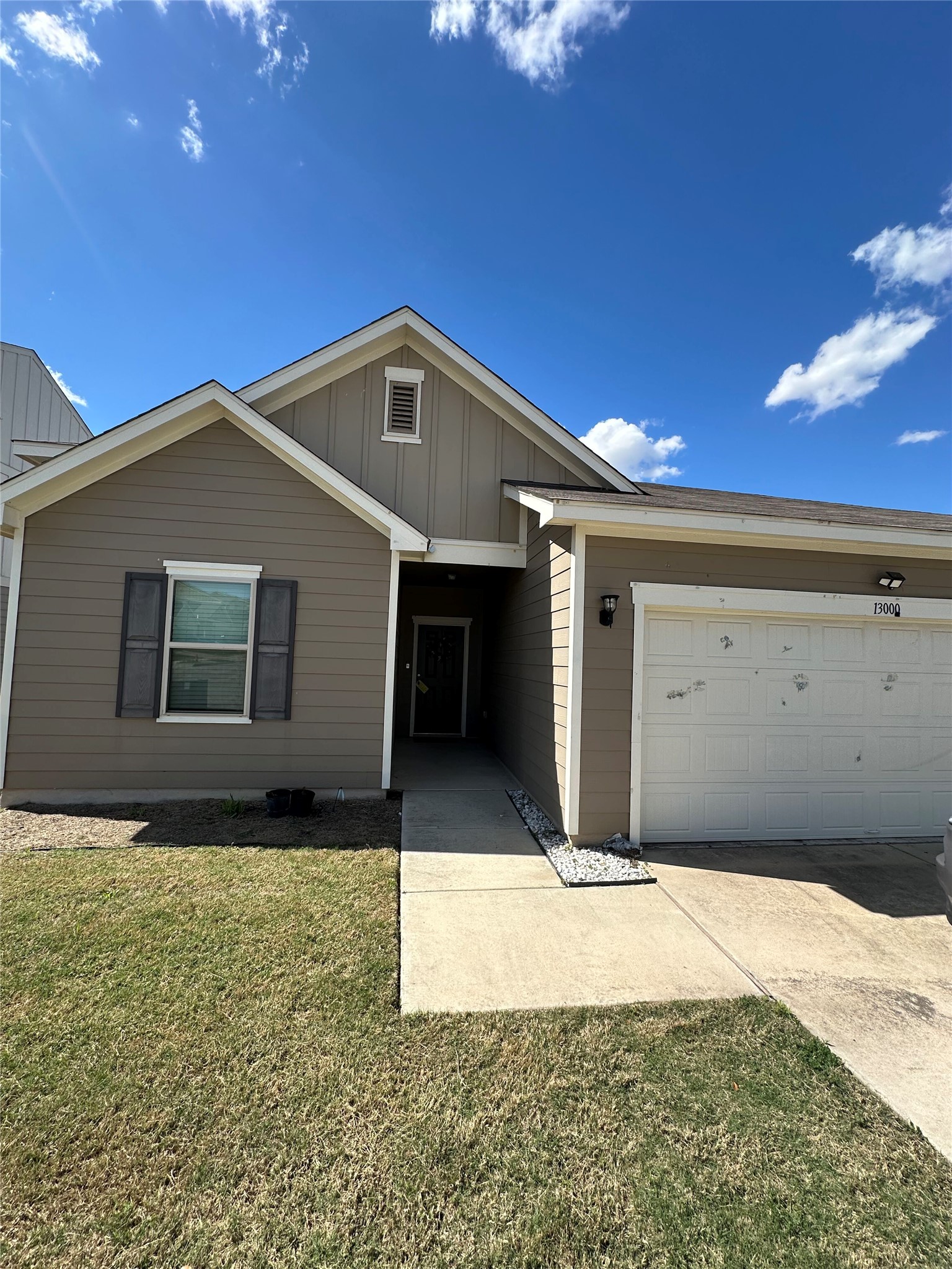 13000 Titanium Street Austin, TX 78754 - Photo 1 of 15 Single story home featuring board and batten siding, a front yard, concrete driveway, and an attached garage