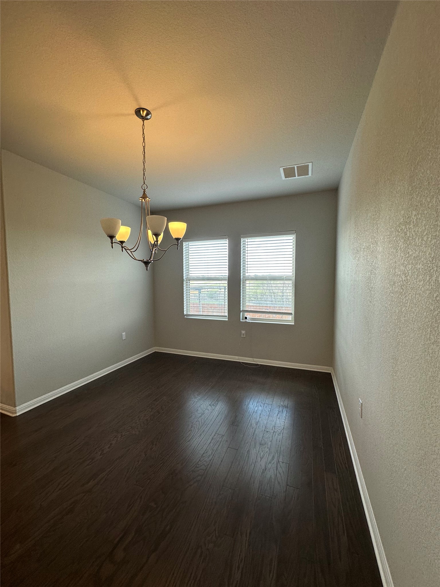 13000 Titanium Street Austin, TX 78754 - Photo 6 of 15 Spare room with a chandelier, dark wood finished floors, and a textured wall