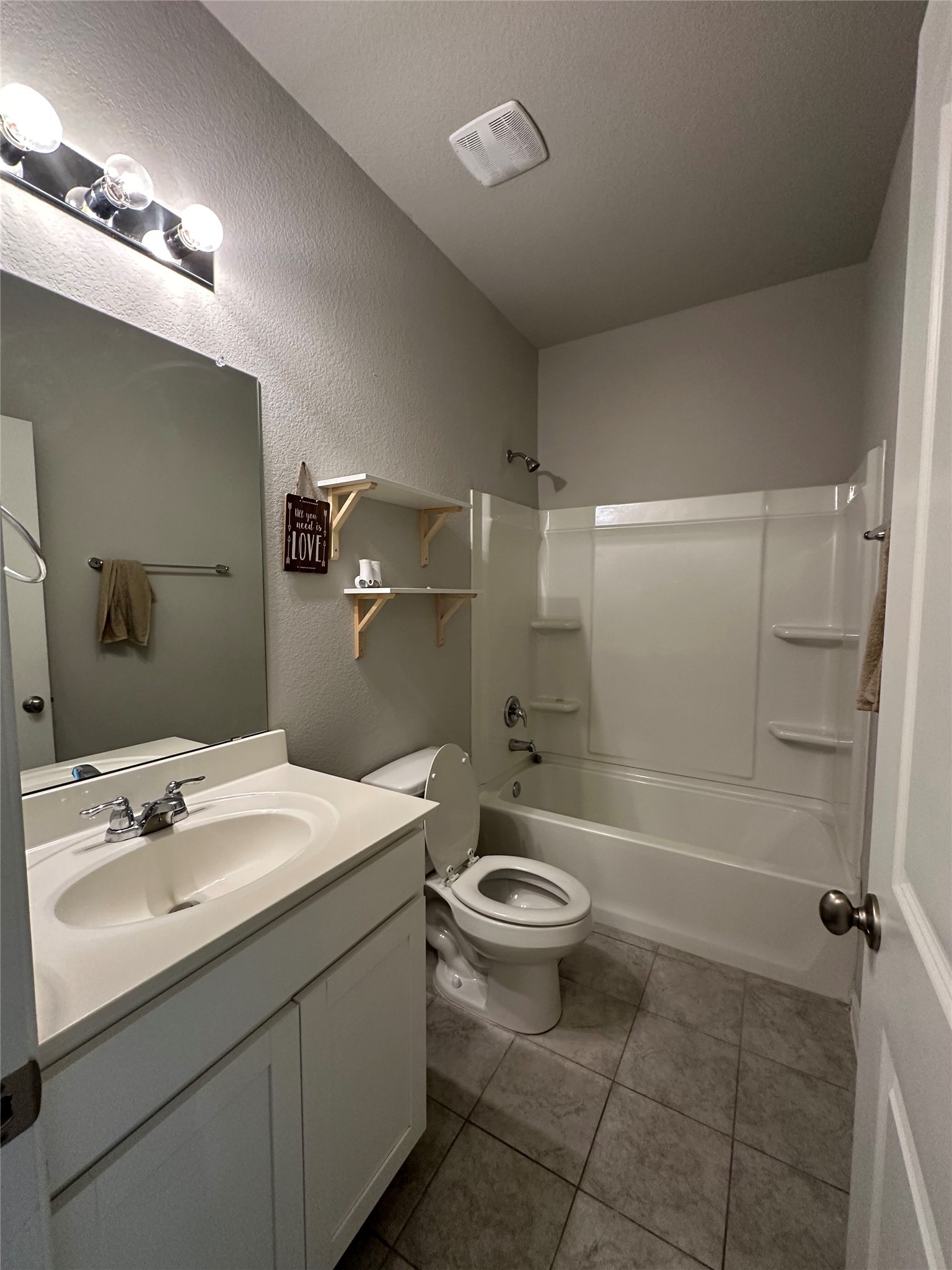 13000 Titanium Street Austin, TX 78754 - Photo 9 of 15 Bathroom featuring vanity, tub / shower combination, a textured wall, and light tile patterned floors