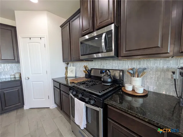 a kitchen with granite countertop stainless steel appliances a stove a sink and a microwave
