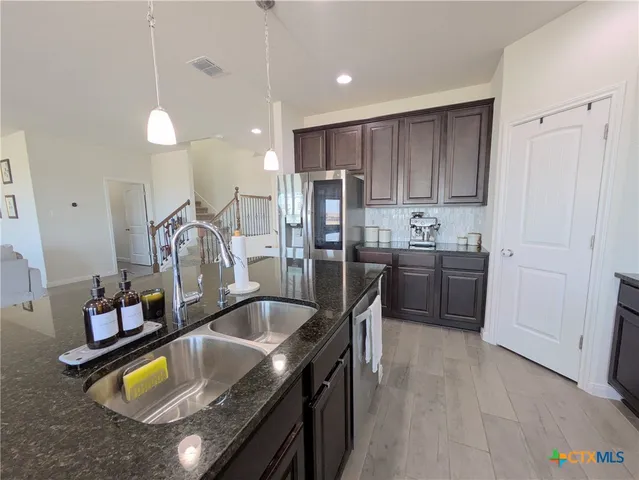 a kitchen with stainless steel appliances granite countertop sink stove and refrigerator