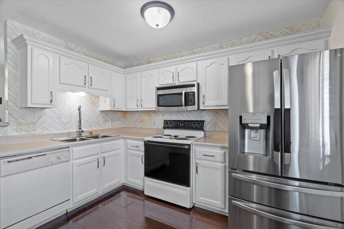 10045 Notting Hill Road Memphis, TN 38016 - Photo 4 of 17 Kitchen with sink, backsplash, stainless steel appliances, dark hardwood / wood-style floors, and white cabinets