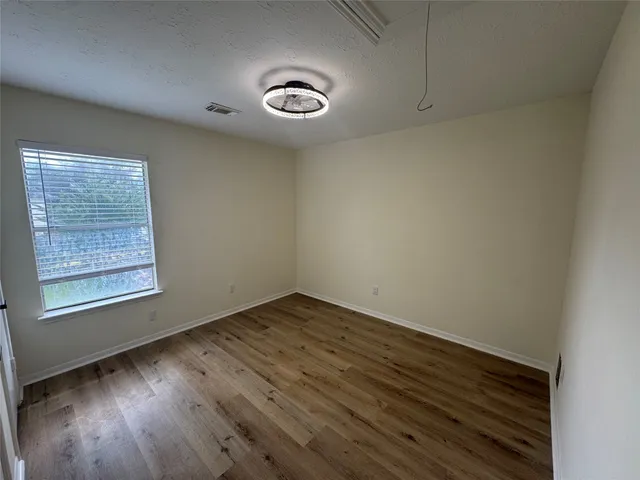 an empty room with wooden floor and windows