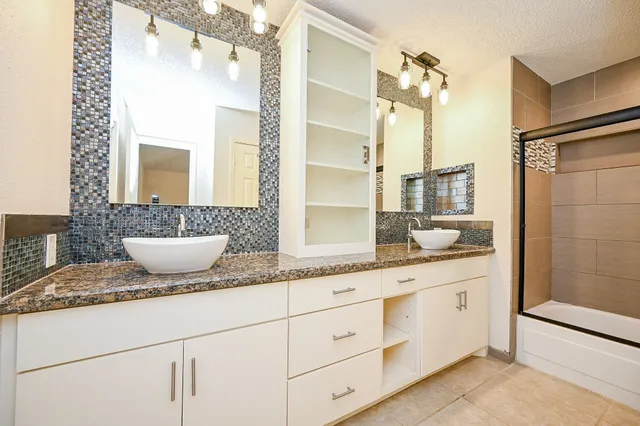 a bathroom with a granite countertop sink a mirror and a shower
