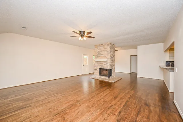a view of empty room with wooden floor and fireplace