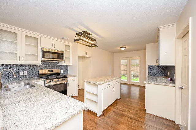 a kitchen with granite countertop a refrigerator stove top oven and sink