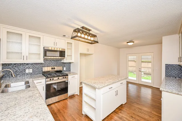 a kitchen with stainless steel appliances kitchen island granite countertop a stove a sink and a microwave