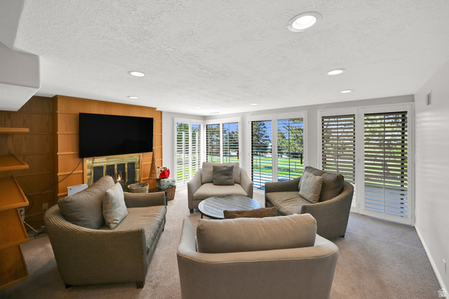 2314 Ridgewood Way Bountiful, UT 84010 - Photo 18 of 26 Integrated fireplace with brass-toned detailing, wood-paneled wall, built-in shelving, recessed ceiling lighting, and large windows with plantation shutters
