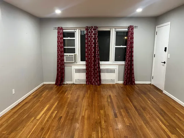 a view of empty room with wooden floor and window