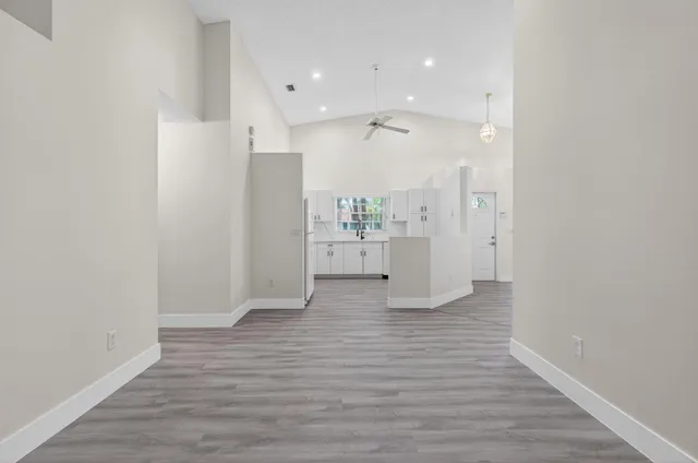 an empty room with wooden floor cabinet and windows