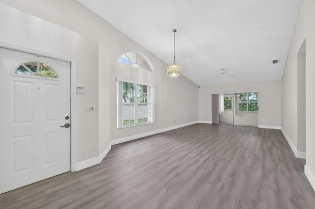 an empty room with wooden floor cabinet and windows