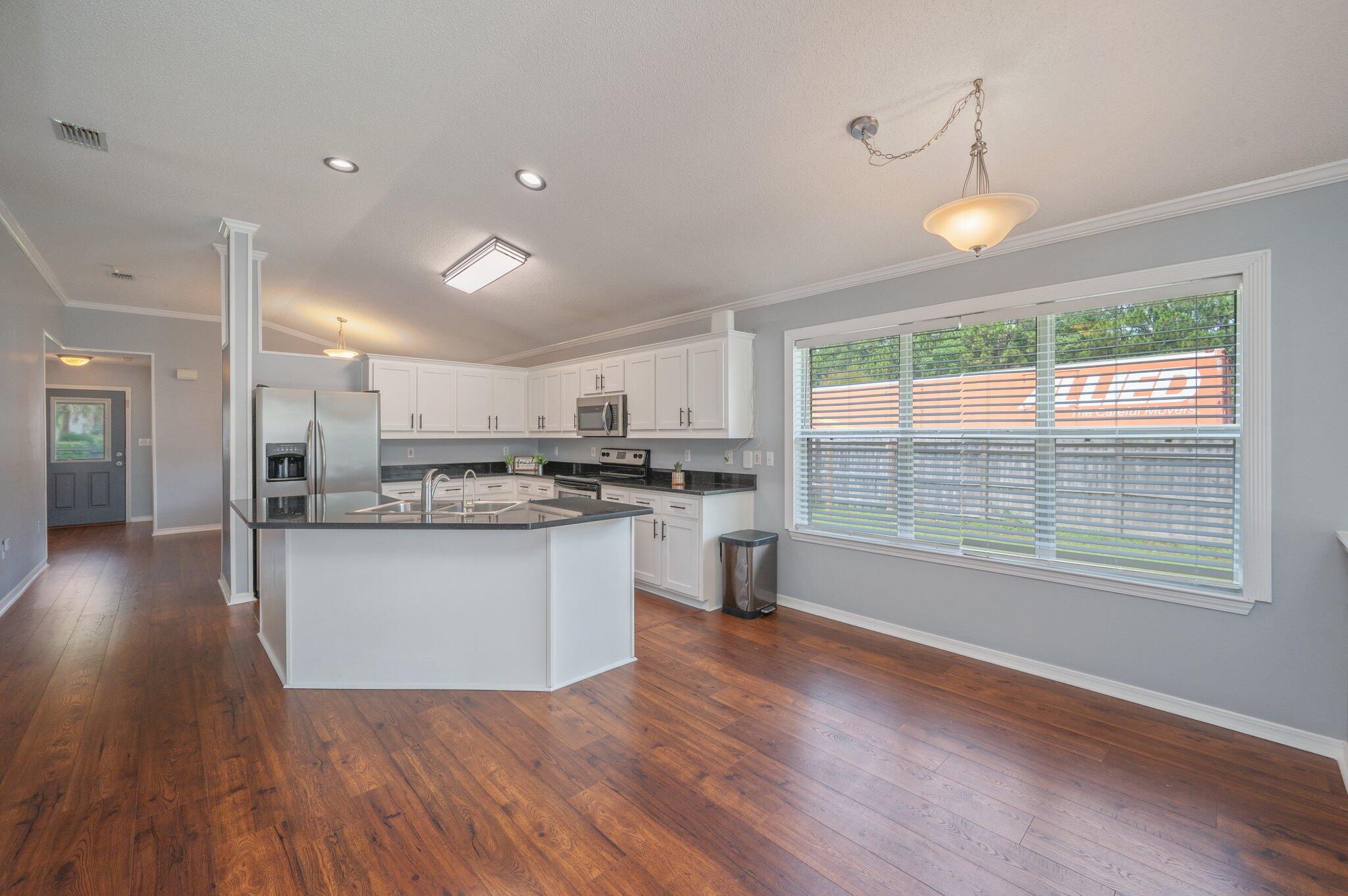 695 Randall Roberts Road Fort Walton Beach, FL 32547 - Photo 18 of 40 a open kitchen with granite countertop a stove top oven a sink and white cabinets with wooden floor
