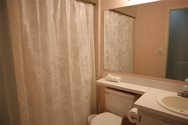a bathroom with a granite countertop sink and a toilet