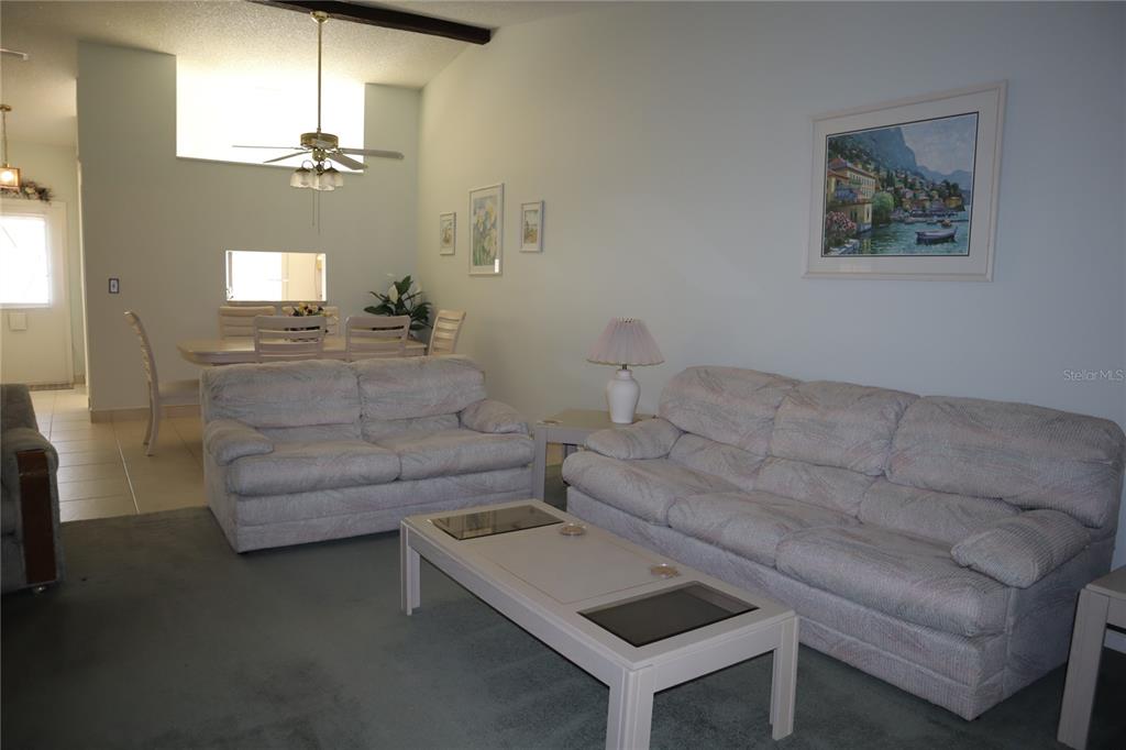 1389 Pine Ridge Circle East, Unit D8 Tarpon Springs, FL 34688 - Photo 9 of 30 a living room with furniture and a chandelier