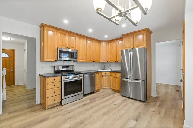 a kitchen with granite countertop a refrigerator a stove top oven and cabinets