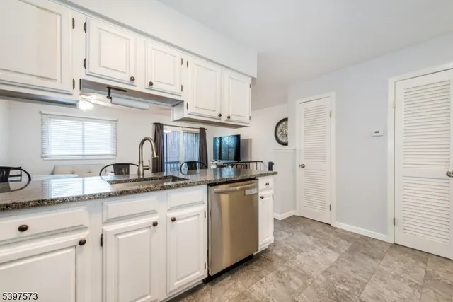 a kitchen with granite countertop stainless steel appliances white cabinets and a sink