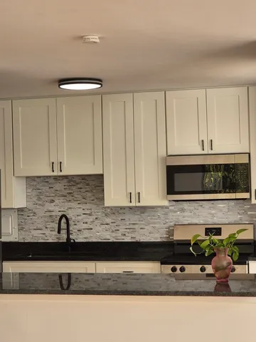 a kitchen with granite countertop white cabinets and a sink