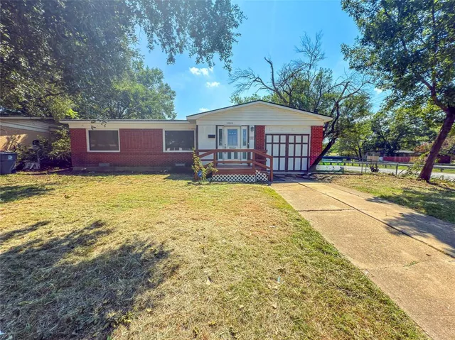 a view of a house with a yard and large tree
