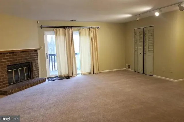 a view of an empty room with a fireplace and a window
