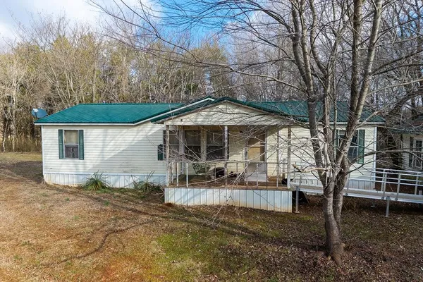 a backyard of a house with table and chairs under an umbrella