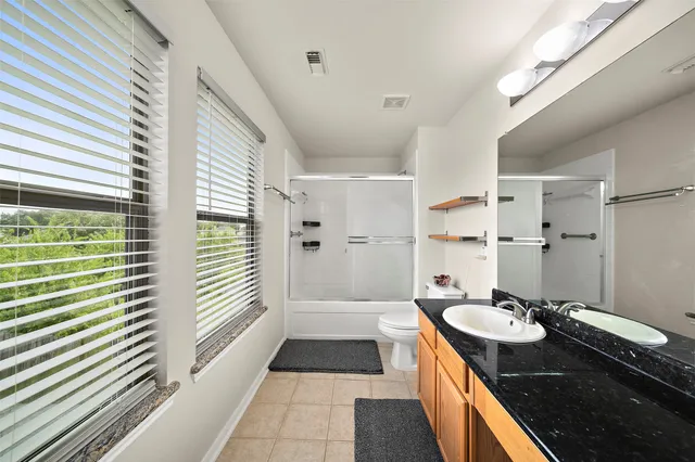 a spacious bathroom with a granite countertop sink a toilet a mirror and shower