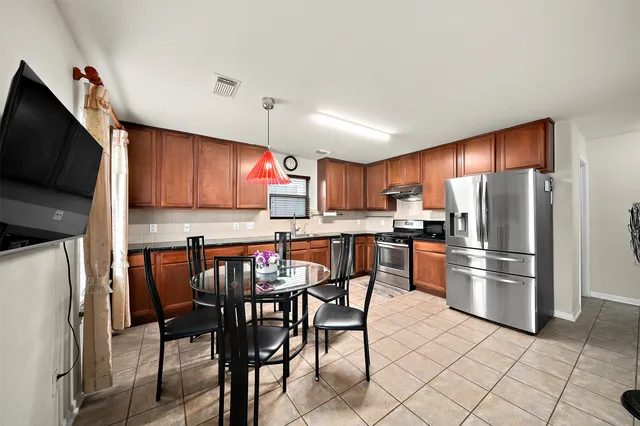 a kitchen with stainless steel appliances granite countertop a refrigerator a stove a sink a table and chairs