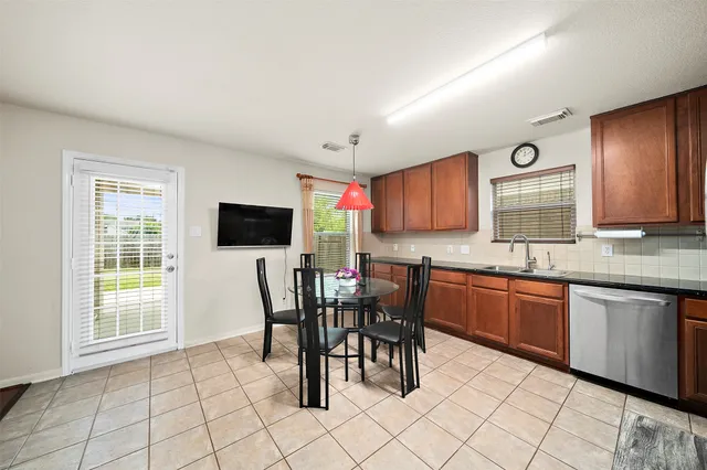 a view of kitchen with granite countertop dining table chairs cabinets and stainless steel appliances