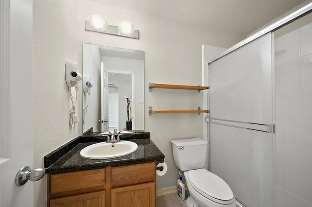 a bathroom with a granite countertop sink toilet a mirror and shower
