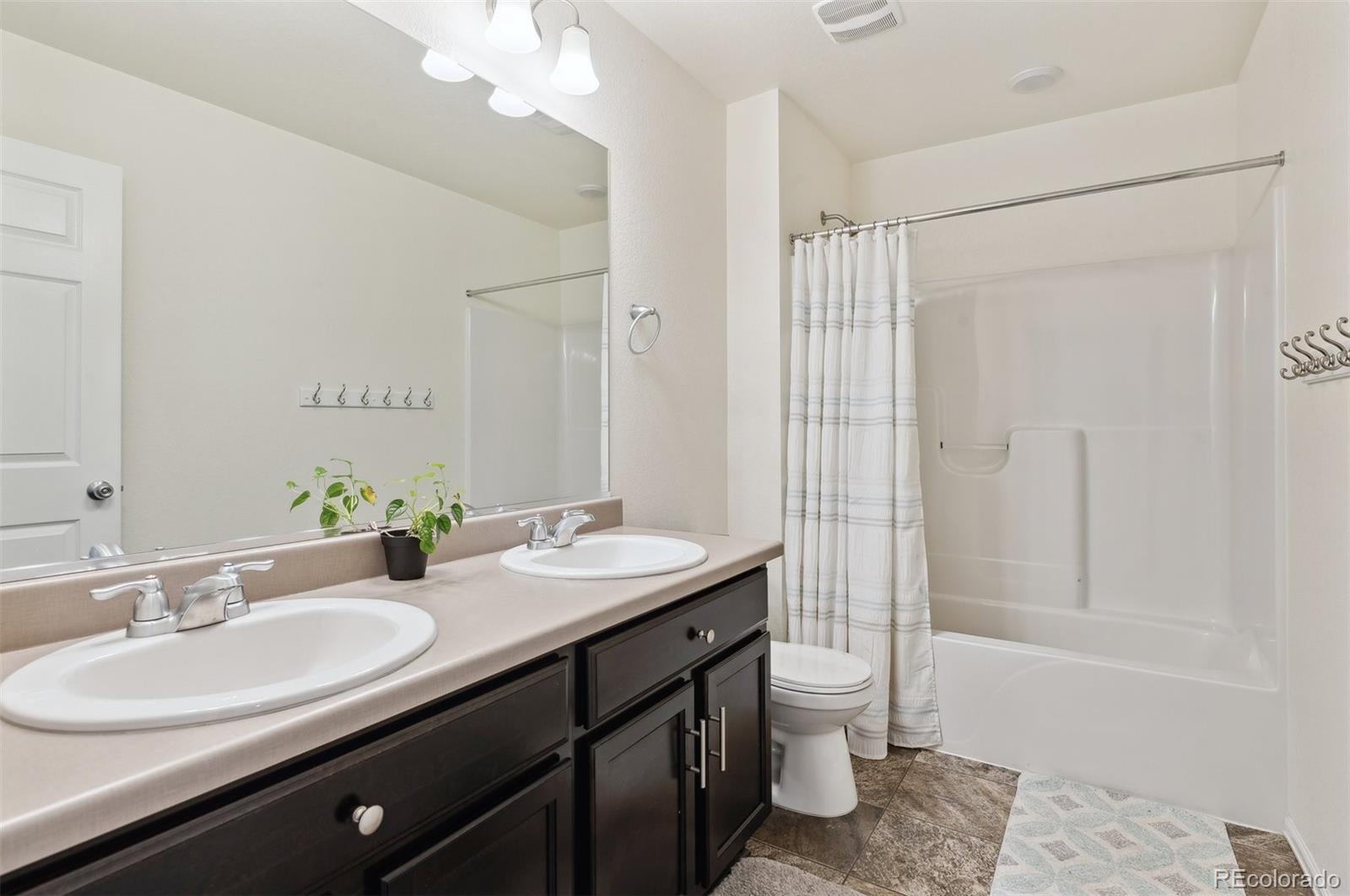2328 Ruby Avenue Brighton, CO 80603 - Photo 20 of 21 a bathroom with a double vanity sink toilet and shower