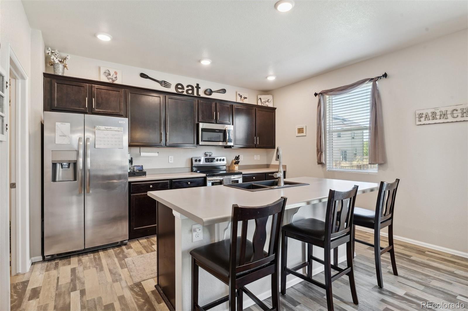 2328 Ruby Avenue Brighton, CO 80603 - Photo 6 of 21 a kitchen with stainless steel appliances a table chairs refrigerator and microwave