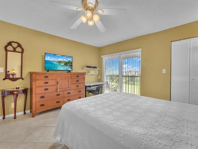 a large bedroom with a bed and a flat tv screen on dresser