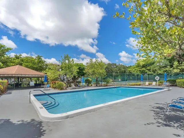 a view of a swimming pool with lawn chairs under an umbrella